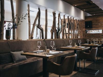 Modernes Restaurant mit Holzakzenten, gemütlichen Sesseln und eingedeckten Tischen.