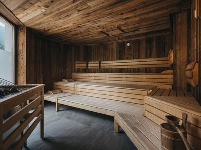 Innere einer Holzsauna mit mehrstufigen Bänken und Saunazubehör.