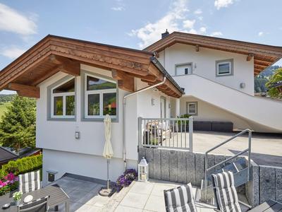 Modernes Ferienhaus mit Holzverkleidung und großer Terrasse in ländlicher Umgebung.
