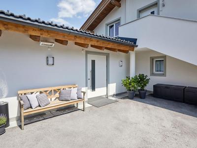 Moderner Außenbereich eines Hotels mit Sitzbank, Sofa und Pflanzen auf hellem Beton.