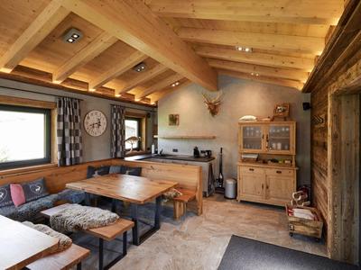 Gemütlicher rustikaler Essbereich mit Holztischen, Bänken und Dachbalken in einer Hotelumgebung.