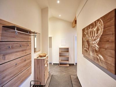 Moderner Eingangsbereich mit Holzdekor, Garderobe und abstraktem Wandbild in warmem Licht.