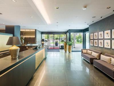 Bright hotel lobby with modern reception, sofas, and artwork on the wall.
