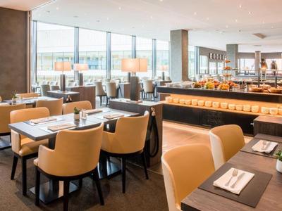 Modern hotel dining area with cozy chairs and buffet section.