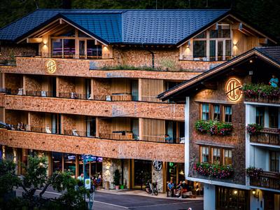 Grand hôtel en bois avec plusieurs balcons et toit foncé, entouré d’arbres.