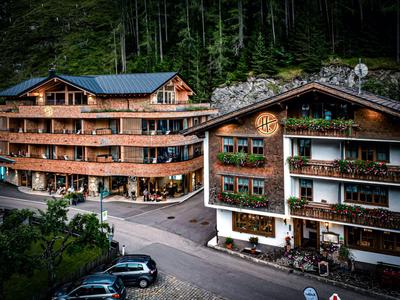 Deux hôtels à plusieurs étages de style alpin avec balcons et forêts vertes en arrière-plan.