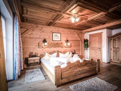 Chambre d'hôtel confortable avec murs en bois, lit double et boiseries décoratives au plafond.