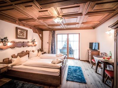 Chambre d'hôtel confortable avec plafond en bois, lit double et vue sur balcon.