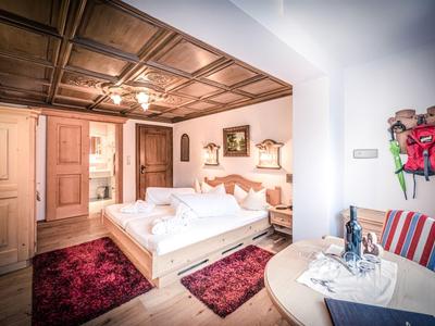 Chambre d'hôtel lumineuse avec lit double, meubles en bois et tapis rouges.