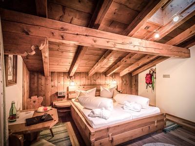 Chambre d'hôtel confortable avec intérieur en bois rustique et lit double sous plafond incliné.