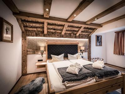 Chambre d'hôtel confortable avec plafond à poutres en bois, lit double et éclairage doux.