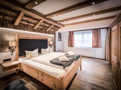Chambre d'hôtel confortable avec meubles en bois, deux lits et grandes fenêtres avec rideaux.
