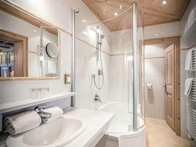 Salle de bain moderne avec douche arrondie et plafond en bois dans un hôtel.