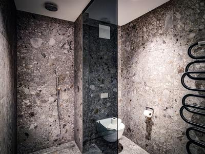 Salle de bain d'hôtel compacte avec murs en marbre, toilette murale et radiateur à serviettes.