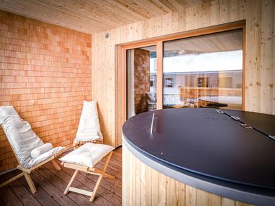 Un balcon d'hôtel calme avec un revêtement en bois, des sièges et un jacuzzi donnant sur l'extérieur.