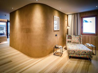 Espace d'attente moderne avec mur incurvé, fauteuil et fenêtre sous une lumière chaude.