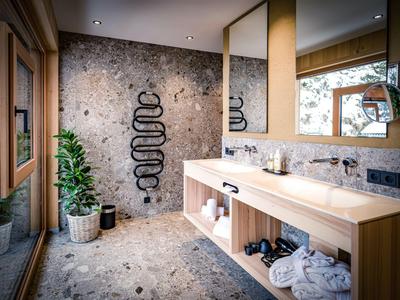 Salle de bain moderne d'hôtel avec double lavabo et radiateur porte-serviettes indépendant sur un mur en pierre grise.