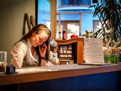 Une réceptionniste d'hôtel parle au téléphone et travaille au comptoir sous un éclairage chaleureux.