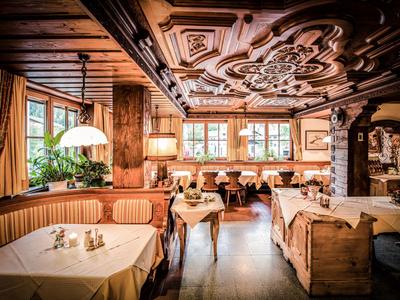 Salle à manger d'hôtel confortable avec meubles en bois, plafond orné et tables dressées.