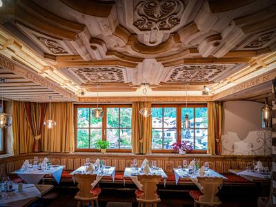 Intérieur de restaurant traditionnel avec tables en bois finement sculptées et plafond décoratif.