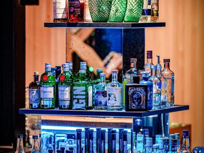 Étagère avec diverses bouteilles d'alcool dans un bar d'hôtel avec un éclairage d'ambiance chaleureux.