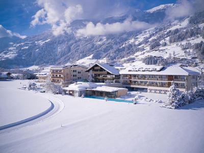 Ein großes Hotel in verschneiter Berglandschaft unter blauem Himmel mit Wolken.