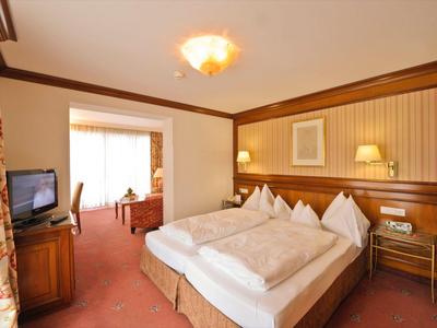 Komfortables Hotelzimmer mit Doppelbett, Fernseher und Schreibtisch in warmen Farbtönen.