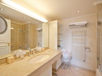 Helles Badezimmer mit großem Spiegel, Waschbecken und Dusche, klar und modern eingerichtet.