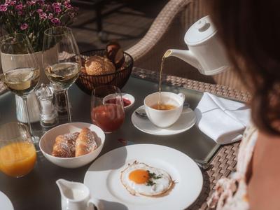 Ein gedeckter Frühstückstisch mit Spiegelei, Eis, Orangensaft und Kaffee in einem Hotelambiente.
