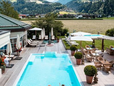 Moderner Hotelpool mit Liegestühlen und Bergblick an einem sonnigen Tag.