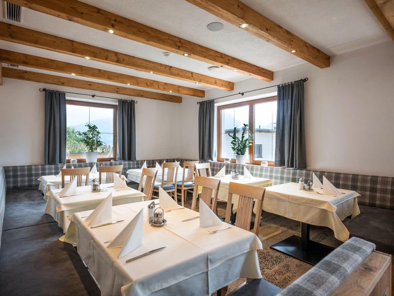 Ristorante luminoso con travi in legno, tavoli con tovaglie bianche e panche imbottite