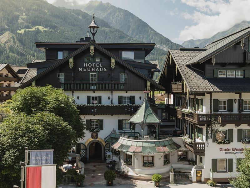 Traditional alpine-style hotel building with mountains in the background