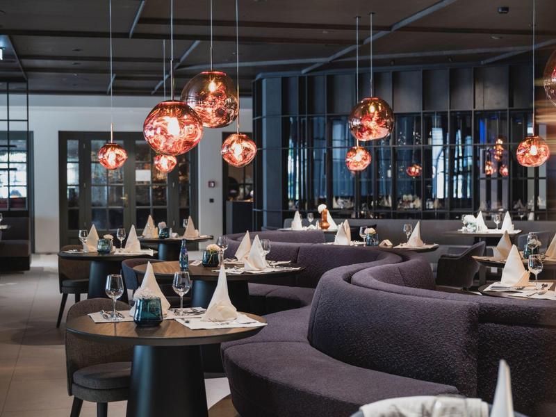 Elegant modern restaurant with curved black sofas and decorative copper pendant lights.