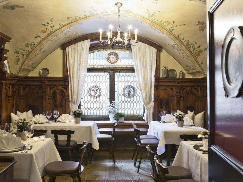 Elegant restaurant with wood paneling, white tablecloths, and chandelier on the ceiling.