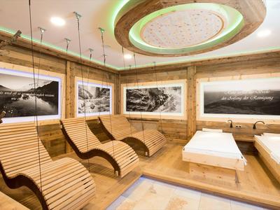 Odpočinková místnost s ergonomickými dřevěnými lehátky, teplým osvětlením a fotografiemi přírody na stěnách.