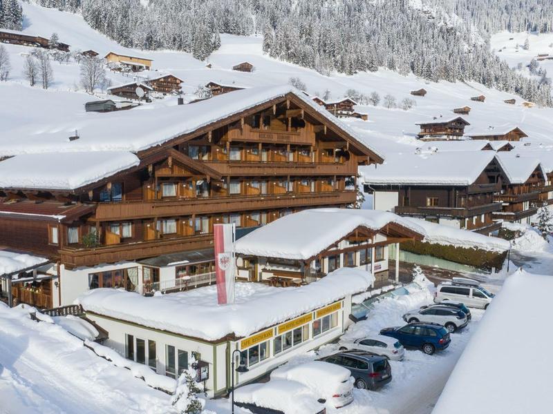 Sněhem pokryté horské chaty a hotel s zaparkovanými auty v zimním středisku.