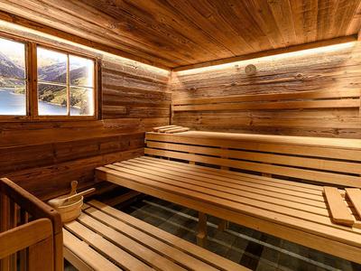 Helles Holzsauna mit Bankreihen, Fenster, Holzverkleidung und indirekter Beleuchtung an der Decke.