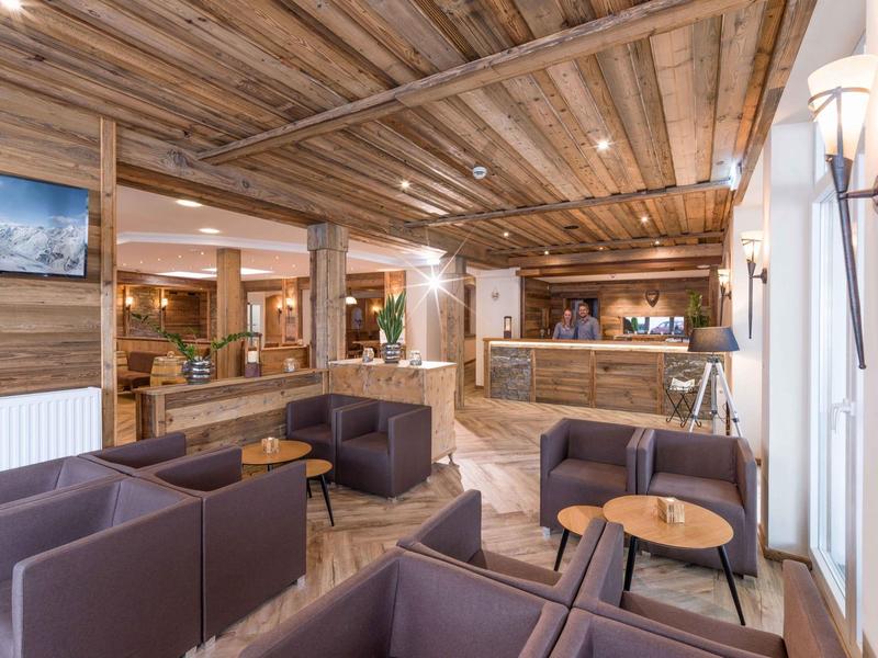 Gemütlicher Hotel-Empfang mit Holzdecken, braunen Sofas und modernem Rezeptionsbereich.