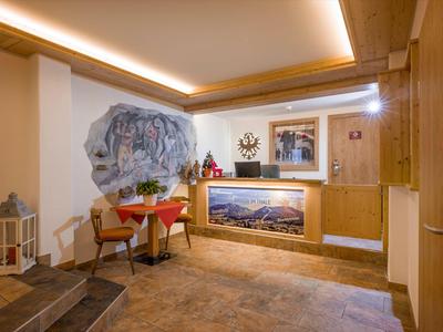 Przytulny pokój wypoczynkowy w hotelu z drewnianymi ścianami, niewielkim stołem i krzesłami, dekoracjami i obrazami na ścianie.