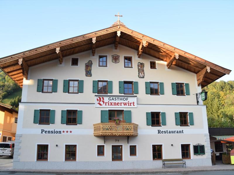 Tradiční alpský dům s balkonem a nápisy pro penzion a restauraci.