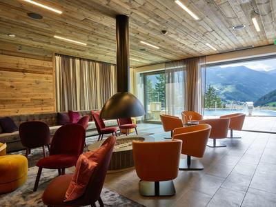 Cozy lounge area with colorful armchairs and large glass front showcasing mountain view.