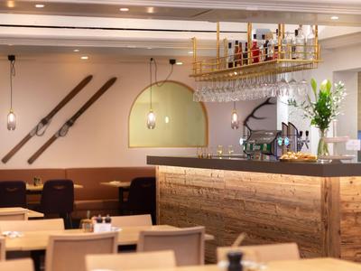 Modern hotel bar with hanging glasses, ski decor, and set tables.