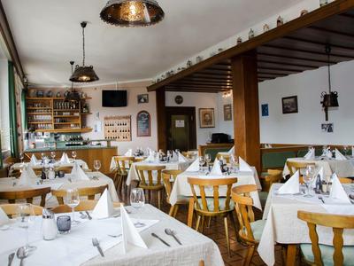 Gezellig restaurant met houten meubels en wit gedekte tafels in een lichte ruimte.