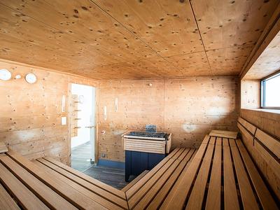 Wood-paneled sauna with benches and small window letting in sunlight.