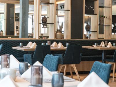 Nowoczesna część restauracyjna z niebieskimi krzesłami i nakrytymi stolikami w jasnej atmosferze.