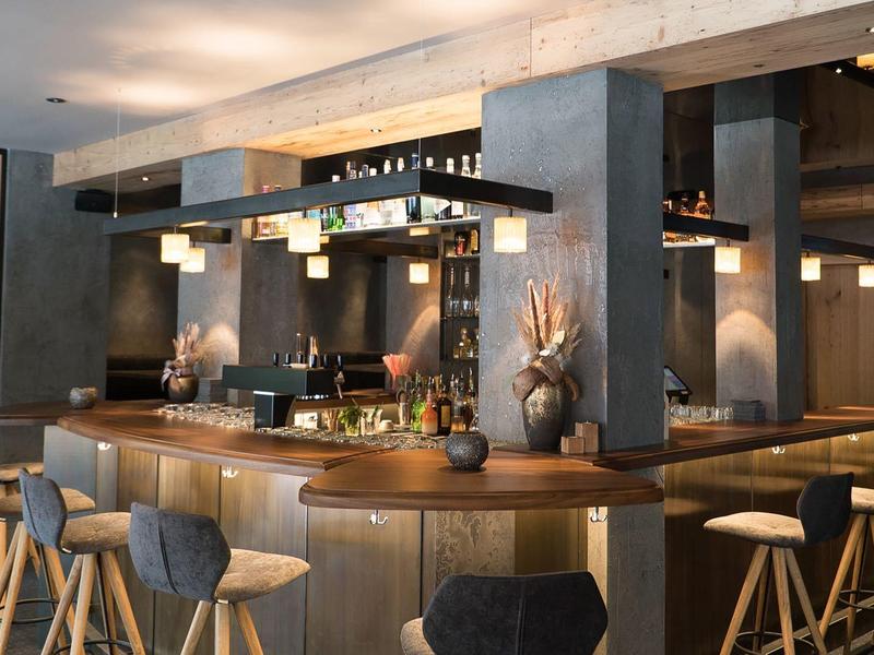 Modern hotel bar with wooden stools and ambient lighting creating a cozy atmosphere.