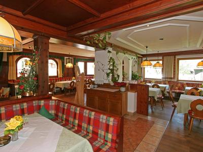 Gemütlicher Gastraum mit Holzmöbeln, karierten Sitzpolstern und dekorativen Lampen.