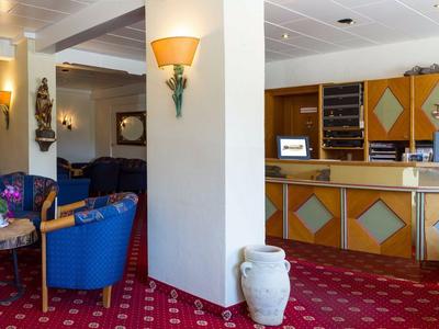 Eleganter Hotellobbybereich mit blauen Sesseln, Teppichboden und einer Rezeption im Hintergrund.