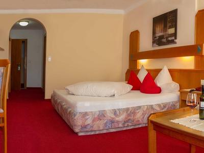 Chambre d'hôtel confortable avec lit double, tapis rouge et mobilier en bois.