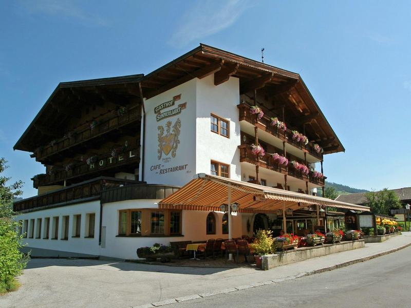 Hôtel traditionnel avec balcons en bois et décorations florales colorées, sous un ciel bleu clair.